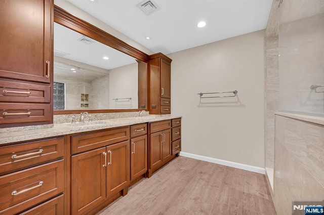 full bathroom with double vanity, visible vents, a sink, wood finished floors, and a walk in shower