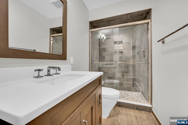 full bath featuring toilet, a stall shower, wood finished floors, and visible vents