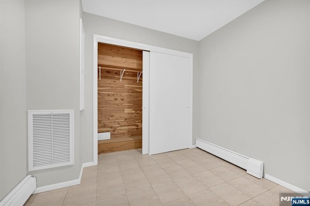 unfurnished bedroom featuring light tile patterned flooring, visible vents, baseboards, baseboard heating, and a closet