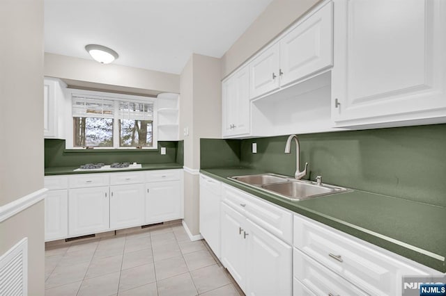 kitchen with dark countertops, light tile patterned floors, white cabinetry, and a sink