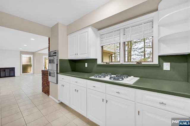 kitchen with light tile patterned floors, white appliances, dark countertops, and white cabinets