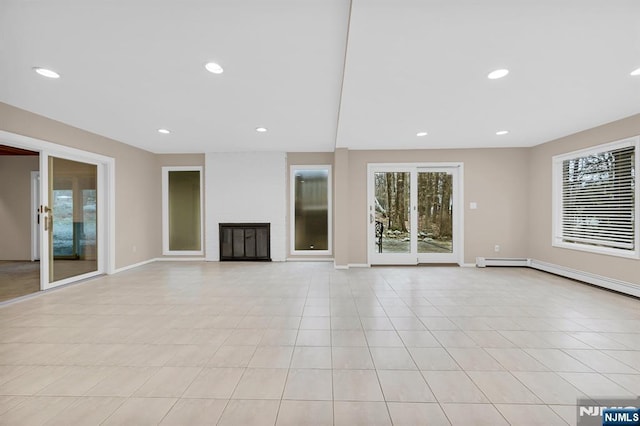 unfurnished living room with light tile patterned floors, recessed lighting, baseboards, and a glass covered fireplace