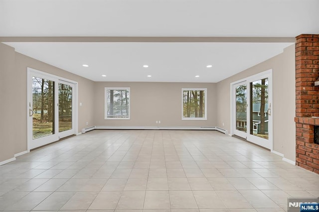 unfurnished living room featuring a healthy amount of sunlight, light tile patterned floors, and baseboards