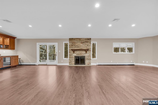 unfurnished living room featuring beverage cooler, a baseboard heating unit, a fireplace, and wood finished floors