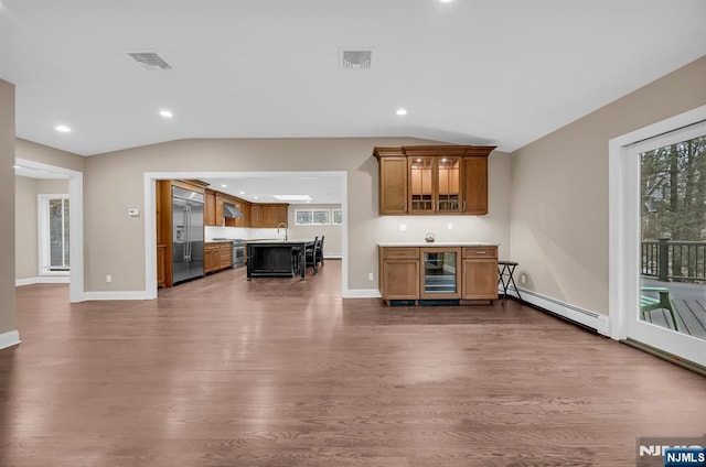 unfurnished living room with beverage cooler, visible vents, dark wood-type flooring, vaulted ceiling, and baseboard heating