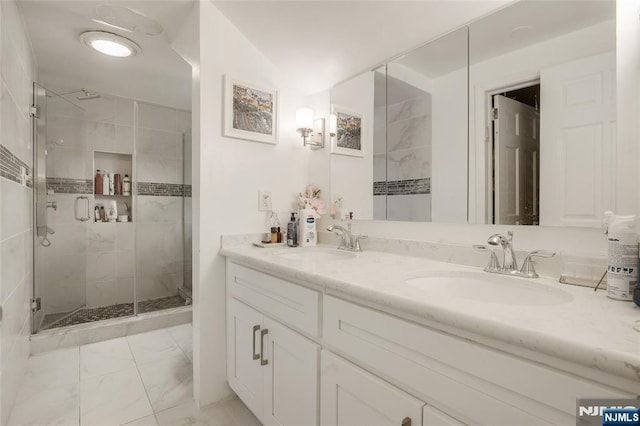 bathroom with double vanity, marble finish floor, a shower stall, and a sink