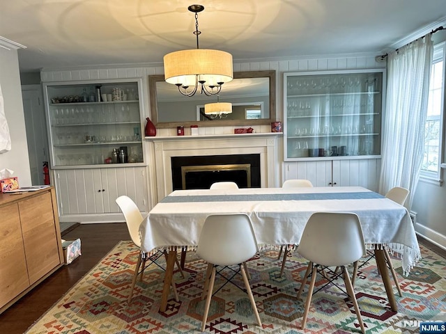 dining space with dark wood-style floors, built in shelves, a fireplace, and crown molding