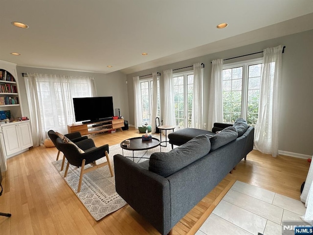 living area featuring a wealth of natural light, baseboards, and light wood finished floors