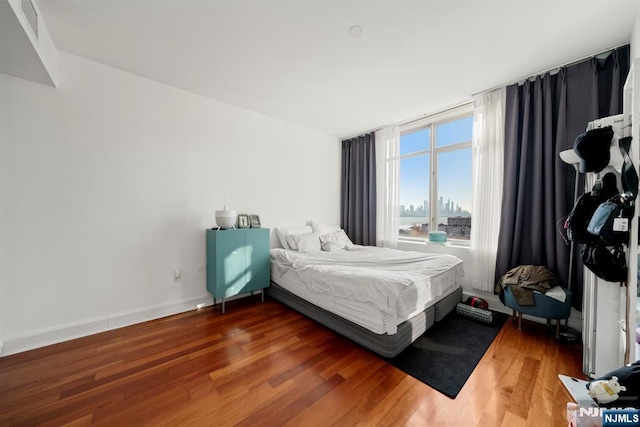 bedroom featuring visible vents, baseboards, and wood finished floors