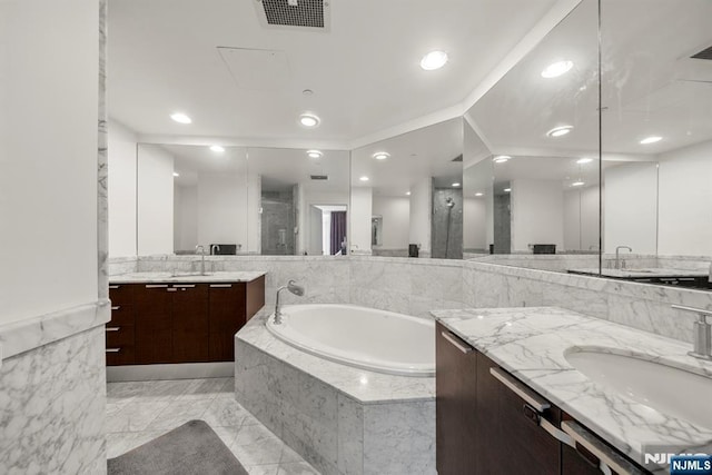 full bath featuring visible vents, a garden tub, two vanities, a stall shower, and a sink