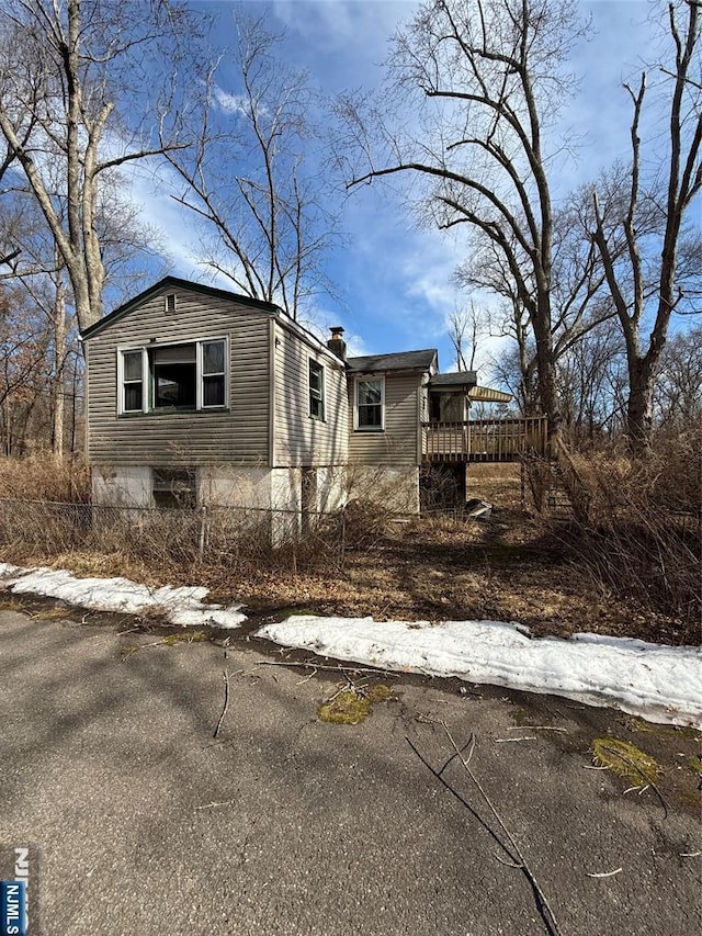 view of front facade with a wooden deck and a chimney