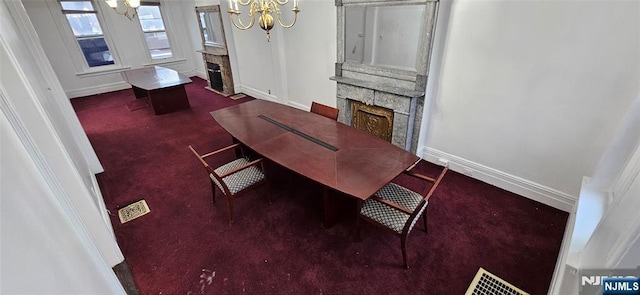 carpeted dining room featuring baseboards, a notable chandelier, and a stone fireplace