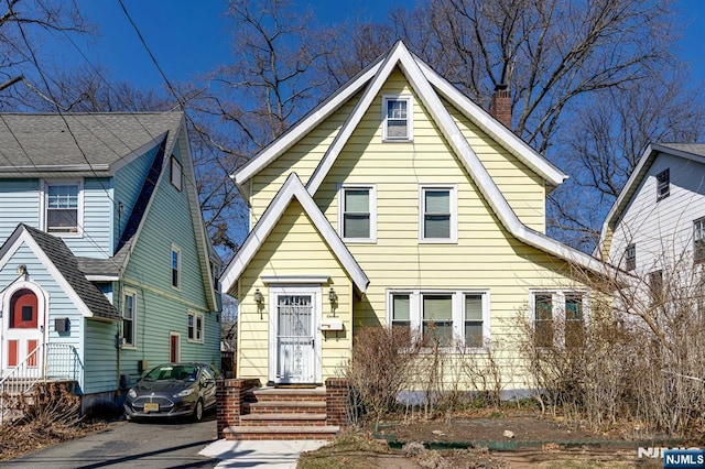 view of front facade featuring entry steps and a chimney