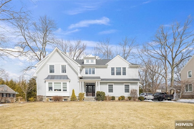 shingle-style home with a front yard, a standing seam roof, roof with shingles, and metal roof