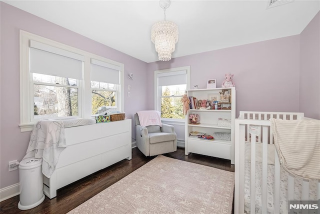 bedroom with visible vents, baseboards, dark wood finished floors, and a notable chandelier