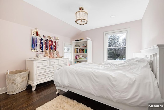 bedroom featuring dark wood-style floors, lofted ceiling, and an inviting chandelier