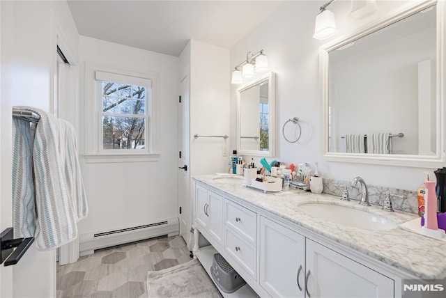 bathroom with double vanity, a baseboard heating unit, and a sink