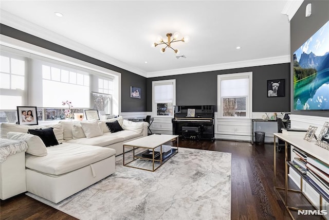 living area with ornamental molding, dark wood-style flooring, wainscoting, and an inviting chandelier