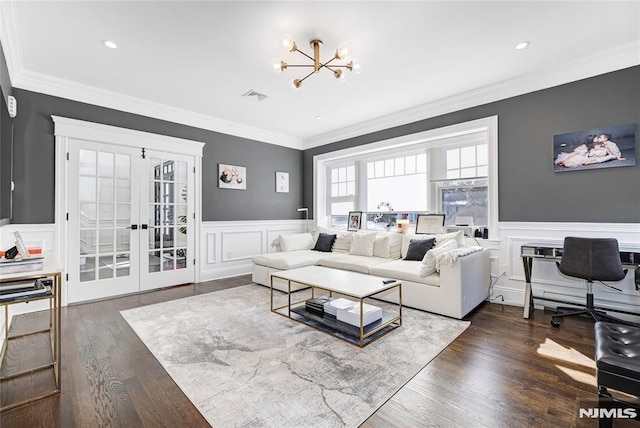 living area with ornamental molding, wainscoting, visible vents, and a notable chandelier