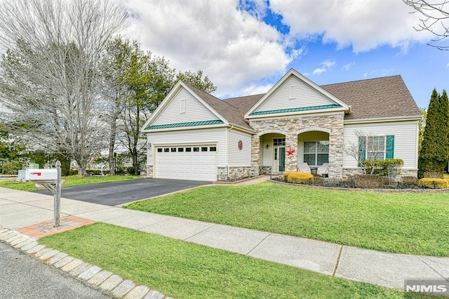 view of front of property featuring stone siding, aphalt driveway, roof with shingles, an attached garage, and a front yard