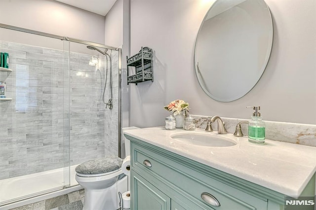 bathroom featuring vanity, a shower stall, and toilet