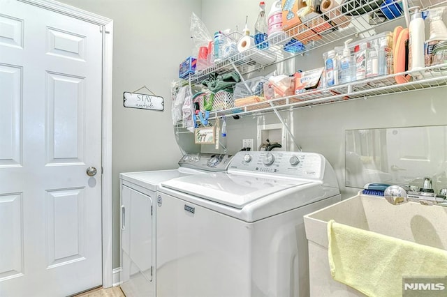 laundry area with laundry area, a sink, and washing machine and clothes dryer