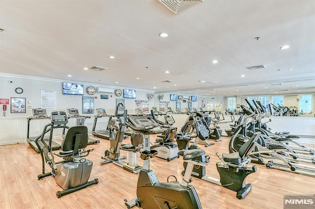 gym with light wood-style flooring, visible vents, and crown molding