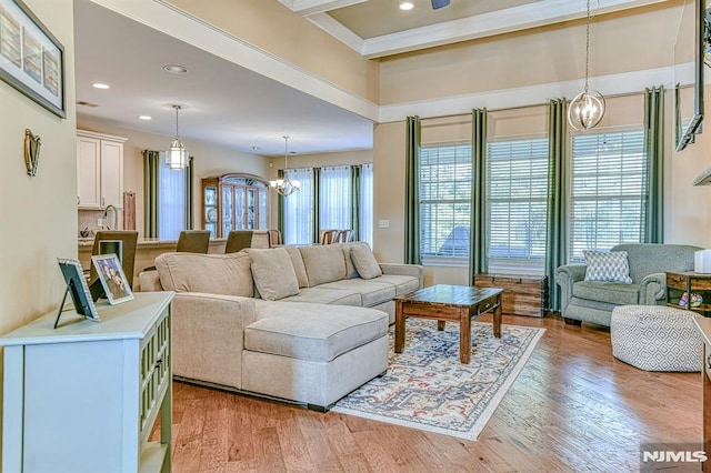 living area featuring recessed lighting, visible vents, light wood-style flooring, an inviting chandelier, and beamed ceiling