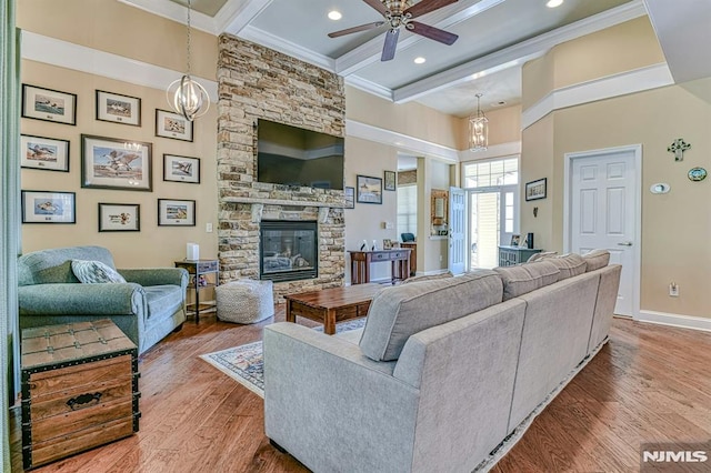 living area with a fireplace, wood finished floors, baseboards, ornamental molding, and beamed ceiling