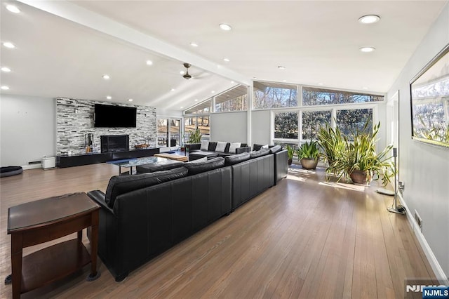 living area featuring lofted ceiling with beams, hardwood / wood-style flooring, plenty of natural light, and a large fireplace