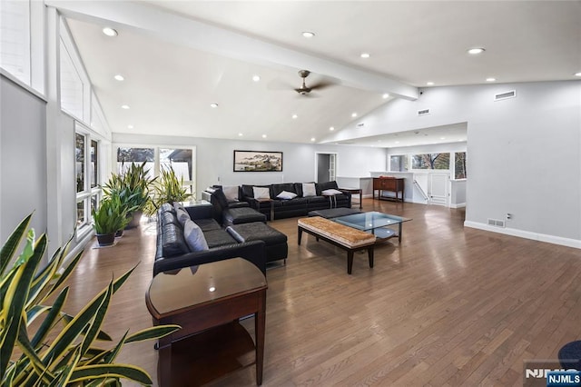 living area featuring vaulted ceiling with beams, plenty of natural light, visible vents, and wood finished floors