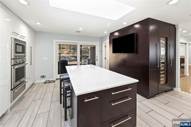 kitchen with stainless steel appliances, a skylight, visible vents, a warming drawer, and modern cabinets