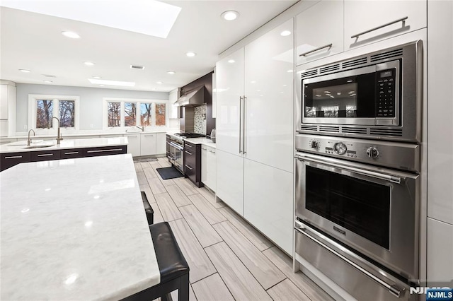 kitchen with a sink, modern cabinets, stainless steel appliances, and a warming drawer