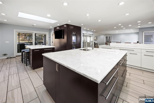 kitchen featuring recessed lighting, a spacious island, a skylight, visible vents, and modern cabinets