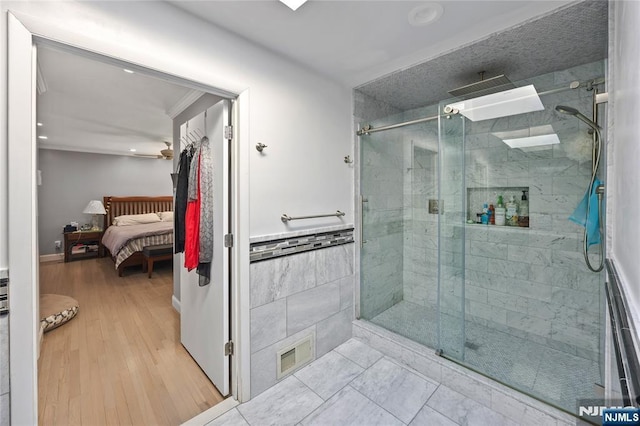 ensuite bathroom featuring tile walls, visible vents, a shower stall, ensuite bath, and wood finished floors