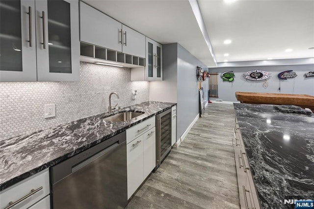 kitchen featuring tasteful backsplash, wine cooler, stainless steel dishwasher, light wood-style floors, and a sink