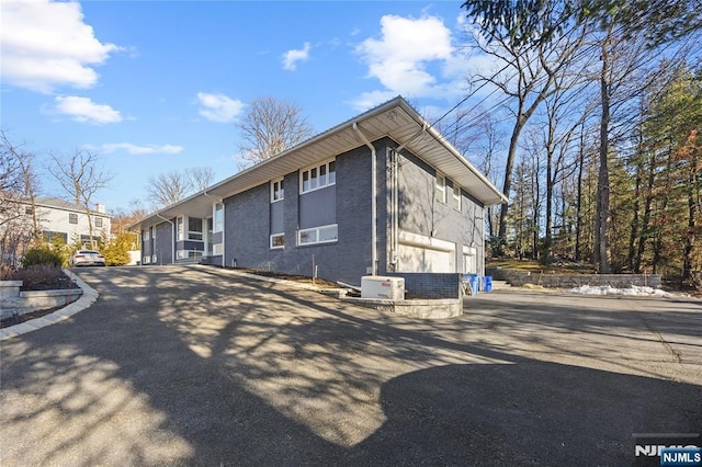 view of side of home with driveway and brick siding