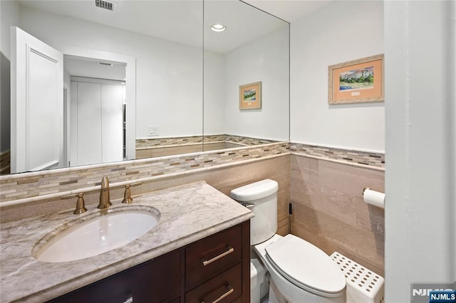 bathroom featuring visible vents, toilet, vanity, tile walls, and recessed lighting