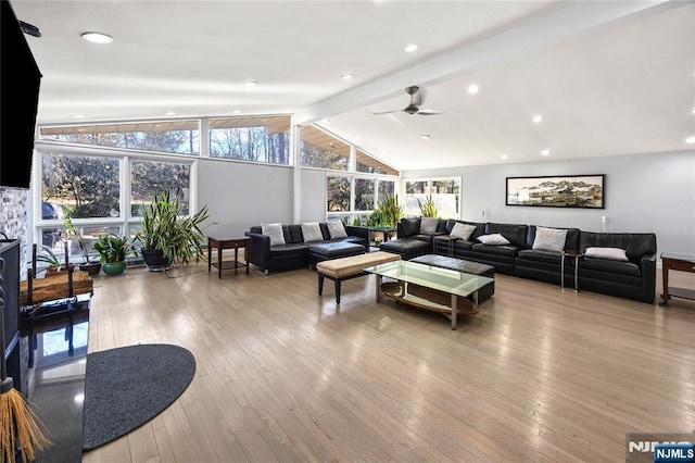 interior space featuring lofted ceiling with beams, a stone fireplace, hardwood / wood-style floors, and a healthy amount of sunlight