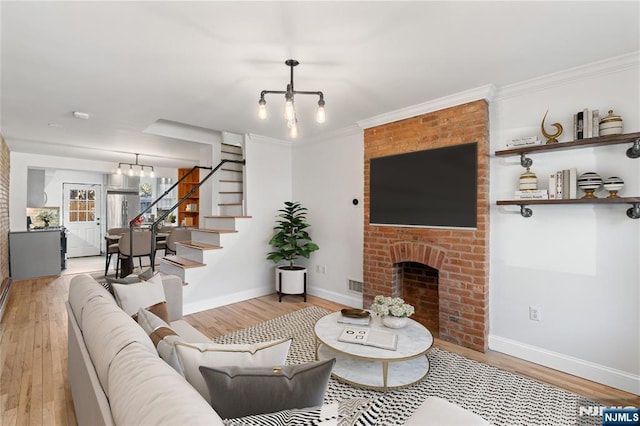 living area with stairway, a brick fireplace, light wood-style flooring, and an inviting chandelier