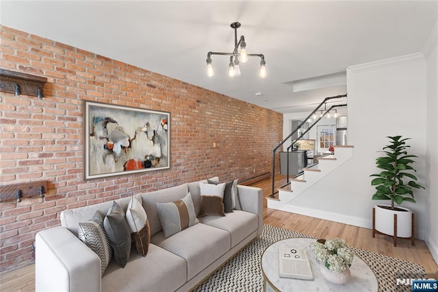 living room featuring stairs, brick wall, wood finished floors, and baseboards