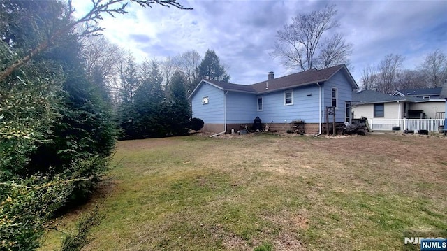 rear view of house featuring a chimney and a yard