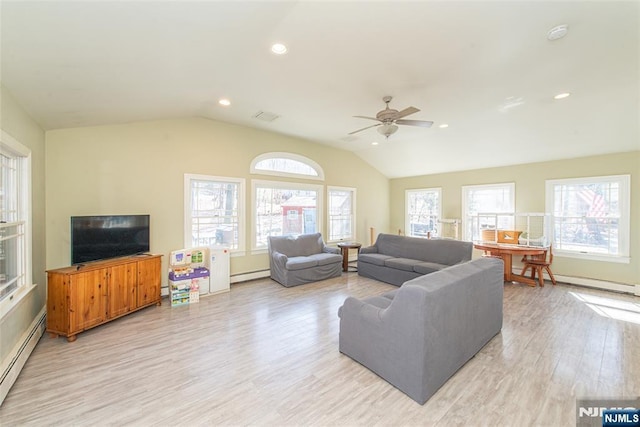 living area featuring a baseboard heating unit, vaulted ceiling, plenty of natural light, and baseboard heating