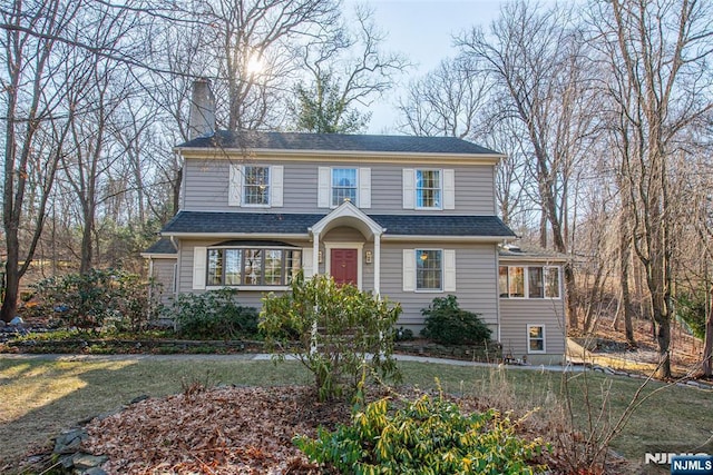 view of front of property featuring a chimney and a shingled roof