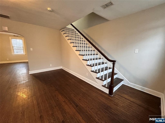 staircase featuring baseboards, visible vents, and wood finished floors