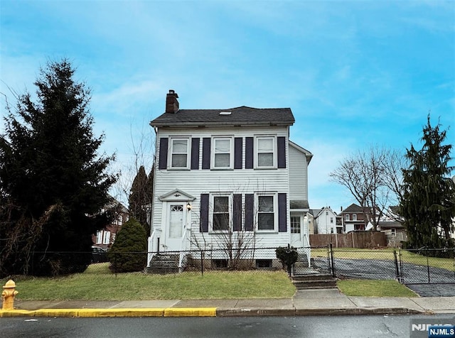 view of front of home with entry steps, a fenced front yard, a chimney, a gate, and a front yard