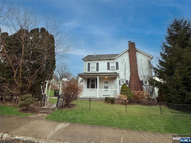 view of front of house with a front lawn, a chimney, a porch, and a fenced front yard