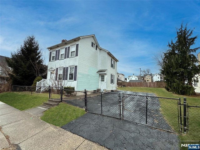 view of property exterior with a chimney, a lawn, a fenced front yard, and a gate