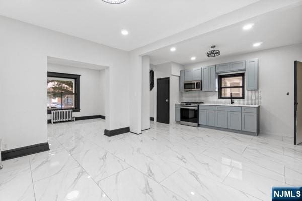 kitchen with marble finish floor, radiator heating unit, stainless steel appliances, and decorative backsplash