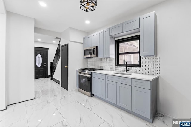 kitchen featuring decorative backsplash, marble finish floor, stainless steel appliances, gray cabinetry, and a sink